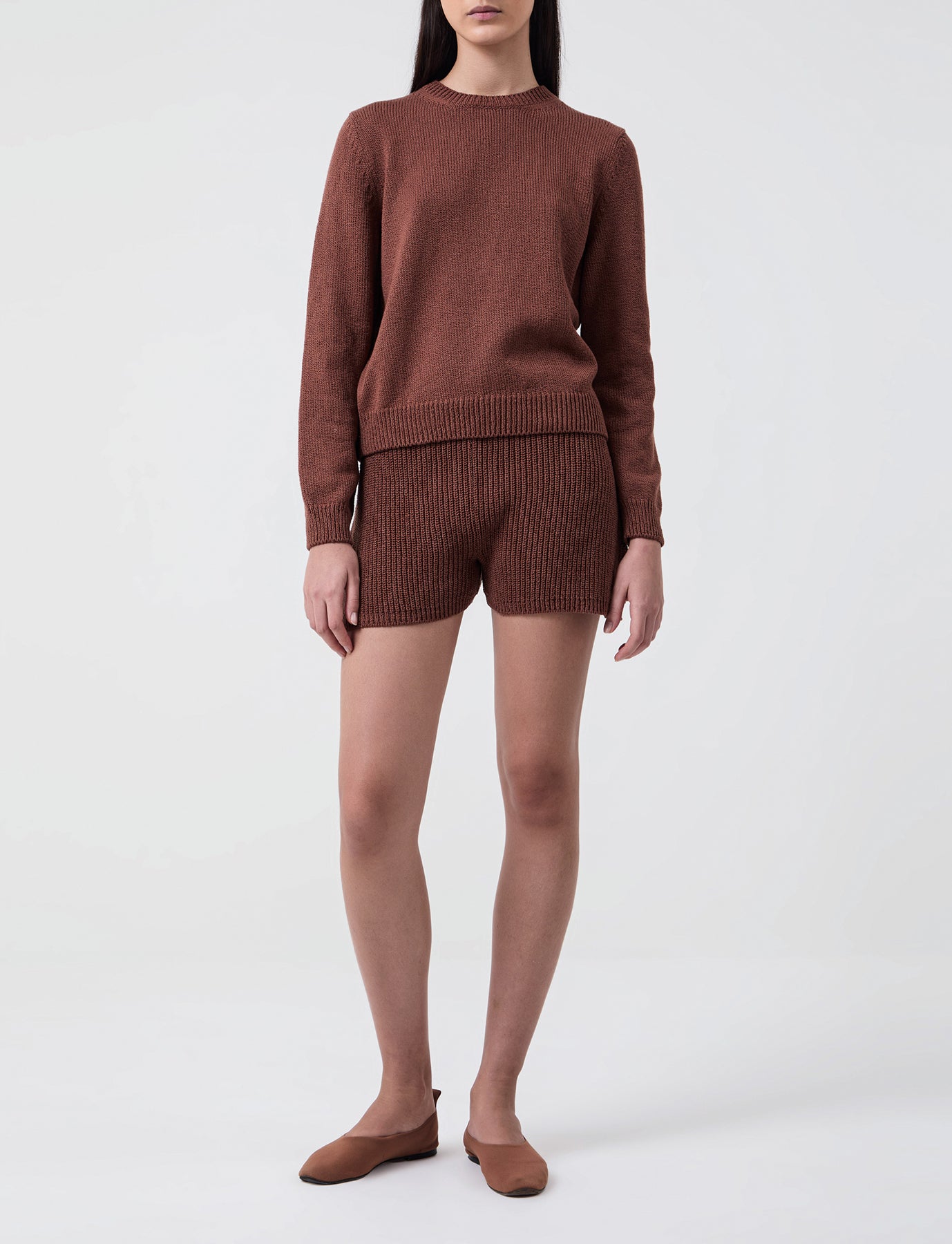 Woman wears Casasola Alba knitted cotton brown shorts with matching crewneck 