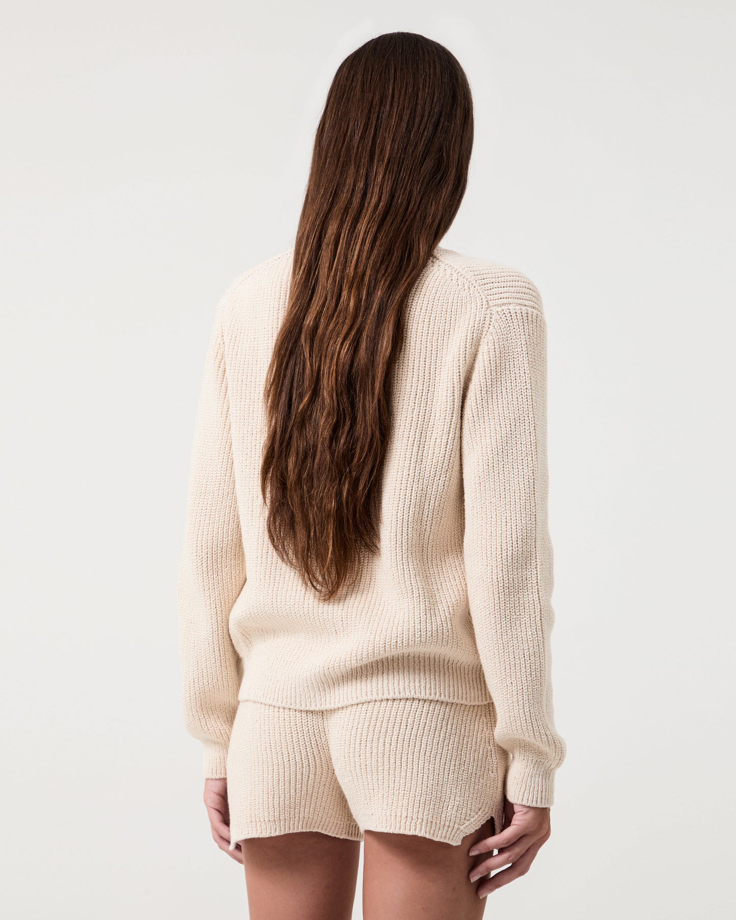 Model wears Casasola  Alba knitted cotton white shorts with matching cardigan - back view
