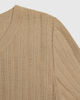 Close-up of a beige knitted sweater with a pointelle textured pattern