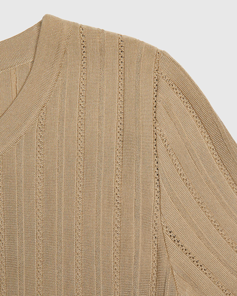 Close-up of a beige knitted sweater with a pointelle textured pattern