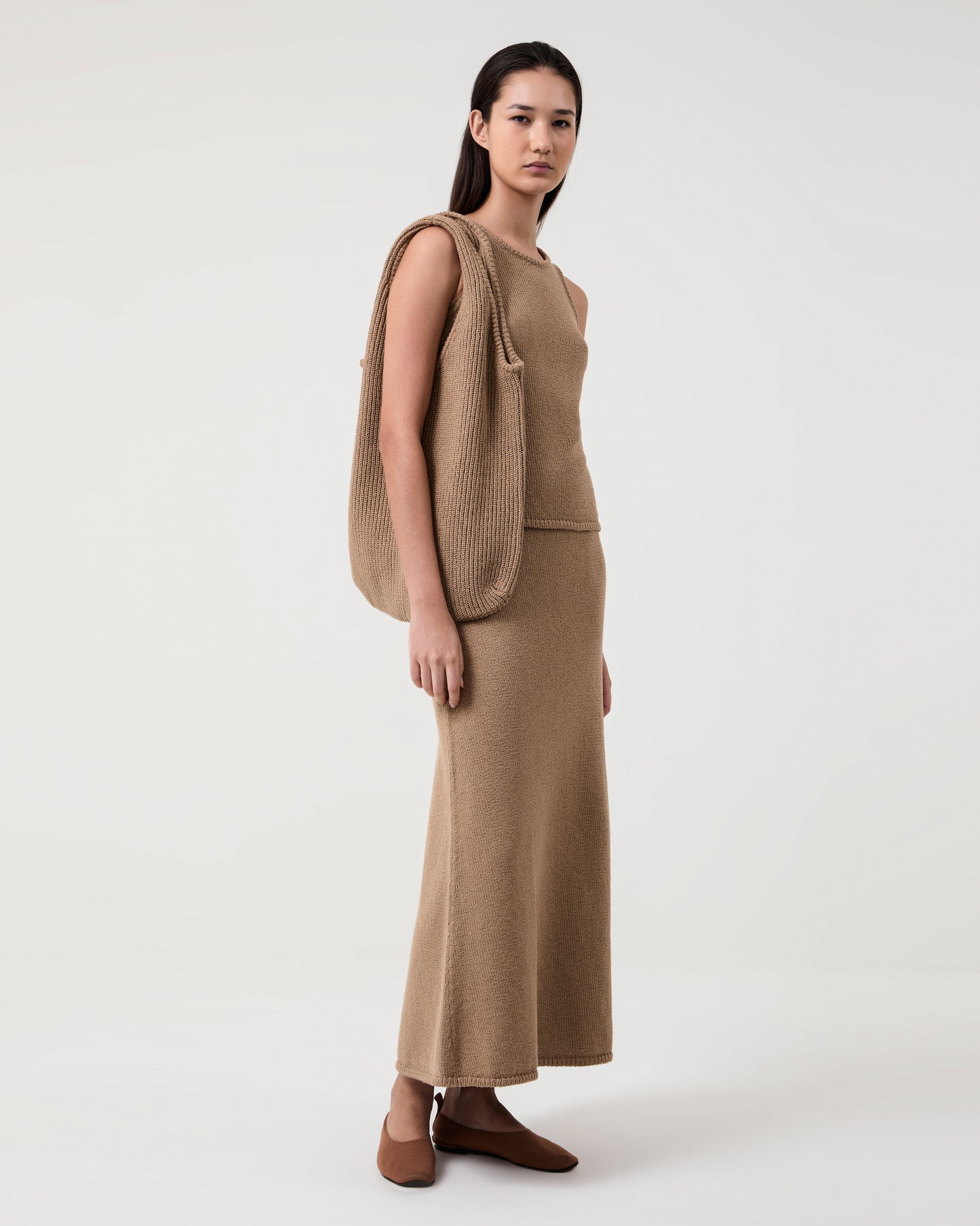 Woman wears Casasola Carolina knitted cotton camel tank top with matching skirt and bag
