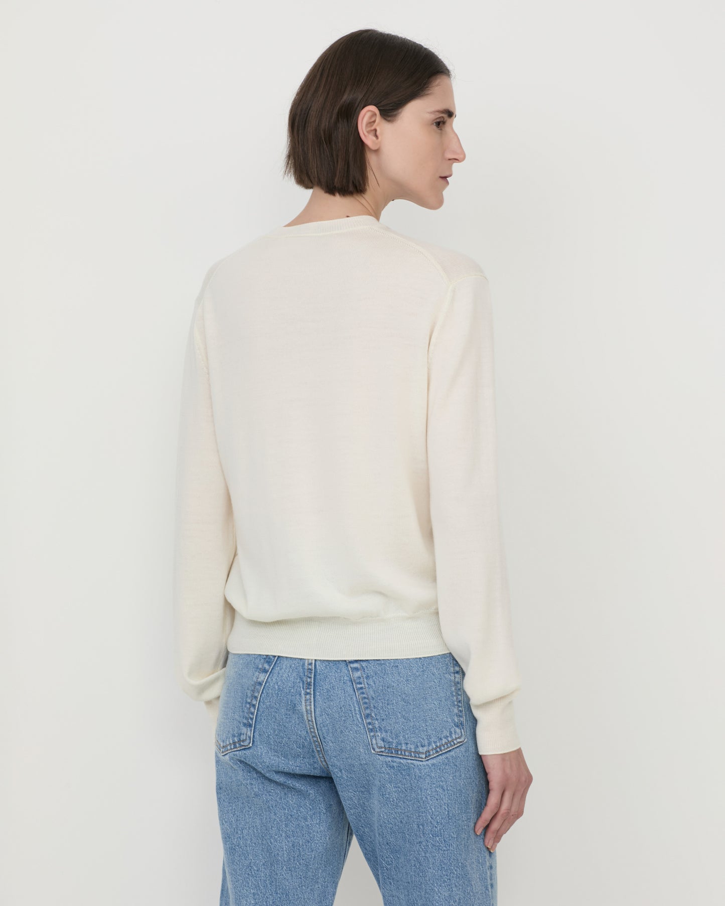 Model wearing Casasola Giada knitted wool classic v-neck sweater in Ivory - back view