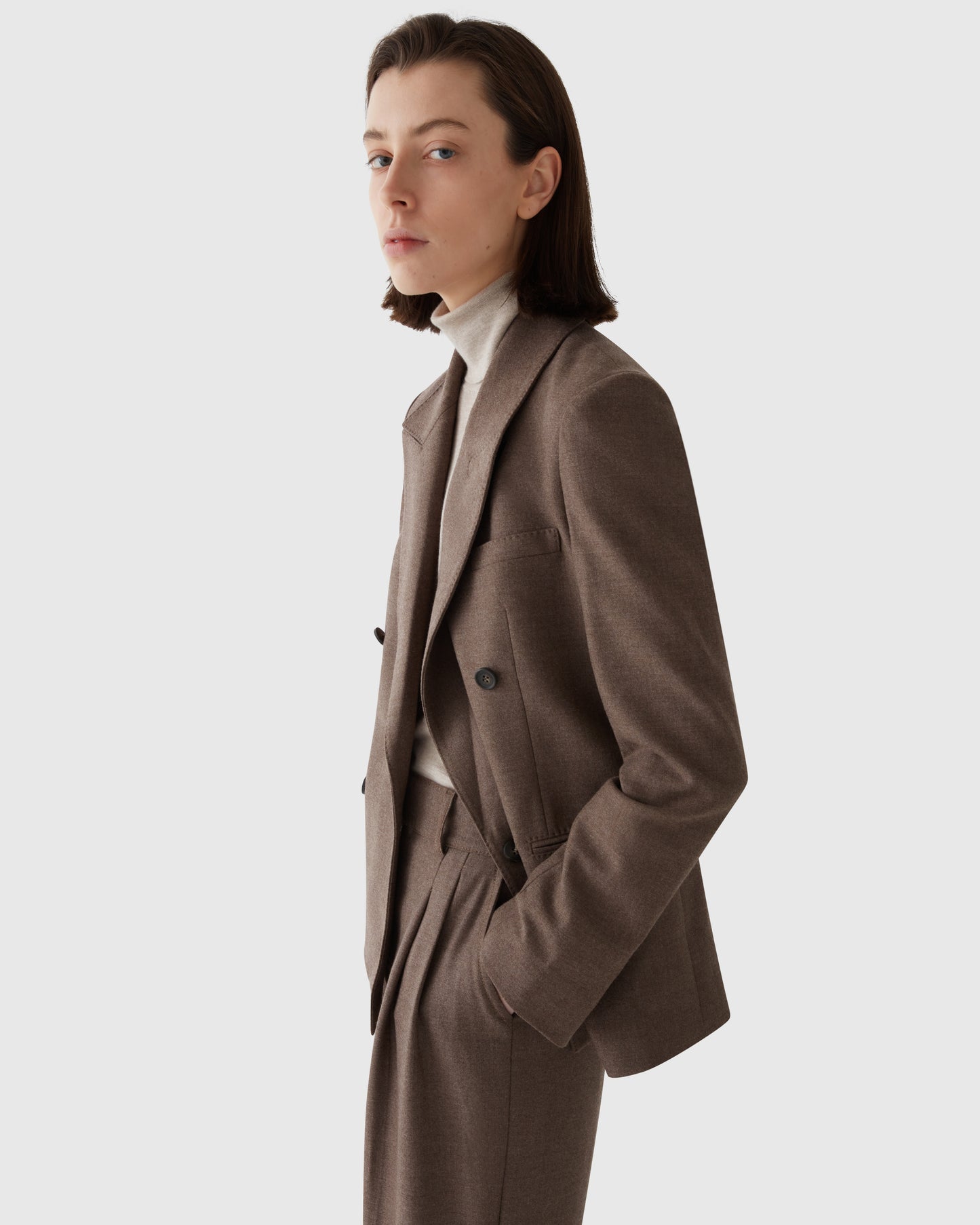 Model wearing CASASOLA 4x1 double-breasted flannel blazer with matching high-waisted trousers and knitted cashmere turtleneck, made in Italy – side view