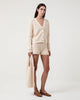Woman wears Casasola Costanza knitted cotton shoulder white bag with matching shorts and cardigan