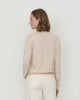 Woman wears Casasola Giada wool V-Neck sweater in Sand - back view