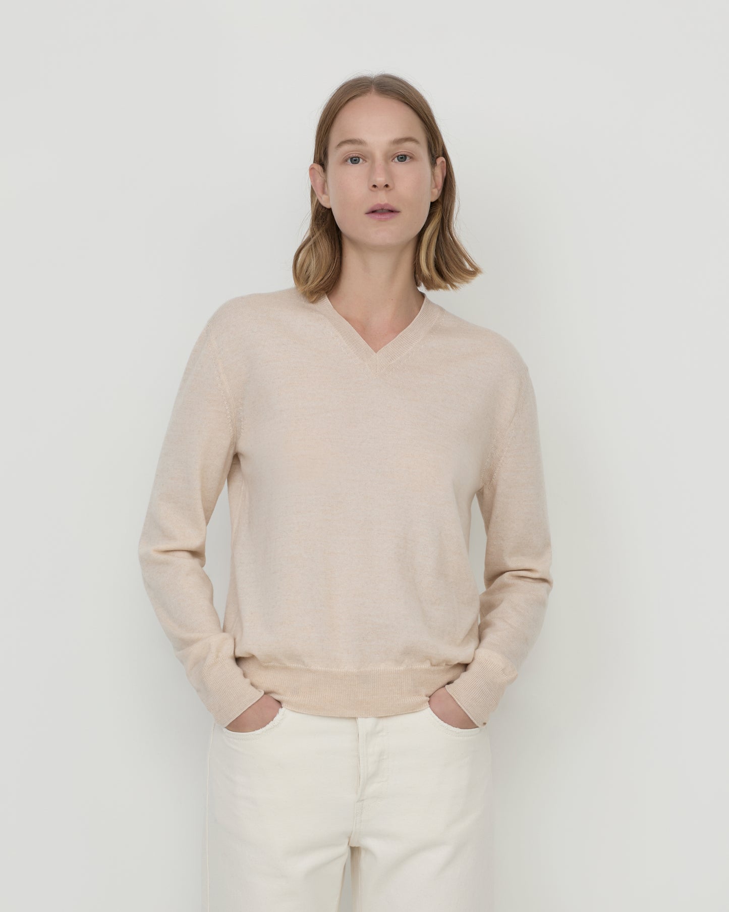 Woman wears Casasola Giada wool V-Neck sweater in Sand - front view