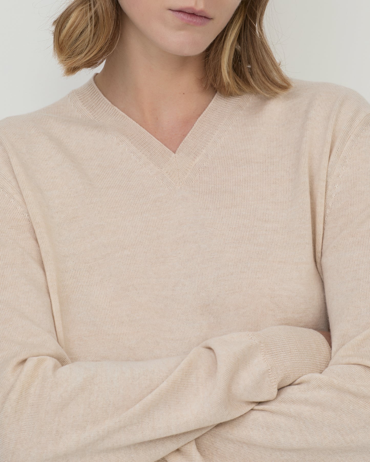 Woman wears Casasola Giada wool V-Neck sweater in Sand - detail view