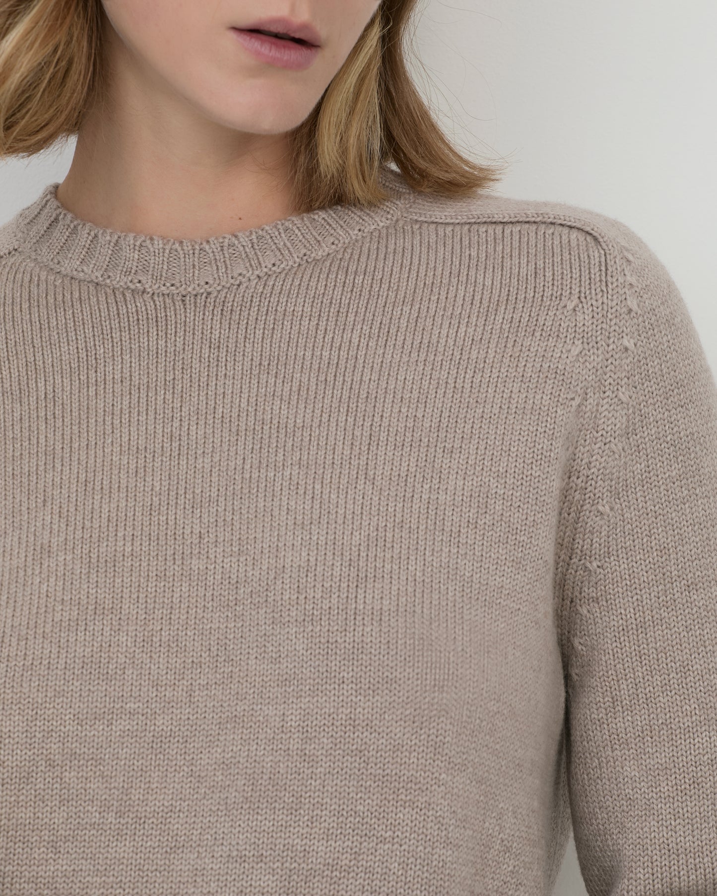Woman wearing Casasola Mia Knitted Merino Wool Saddle Shoulder Crewneck in Beige - detail view