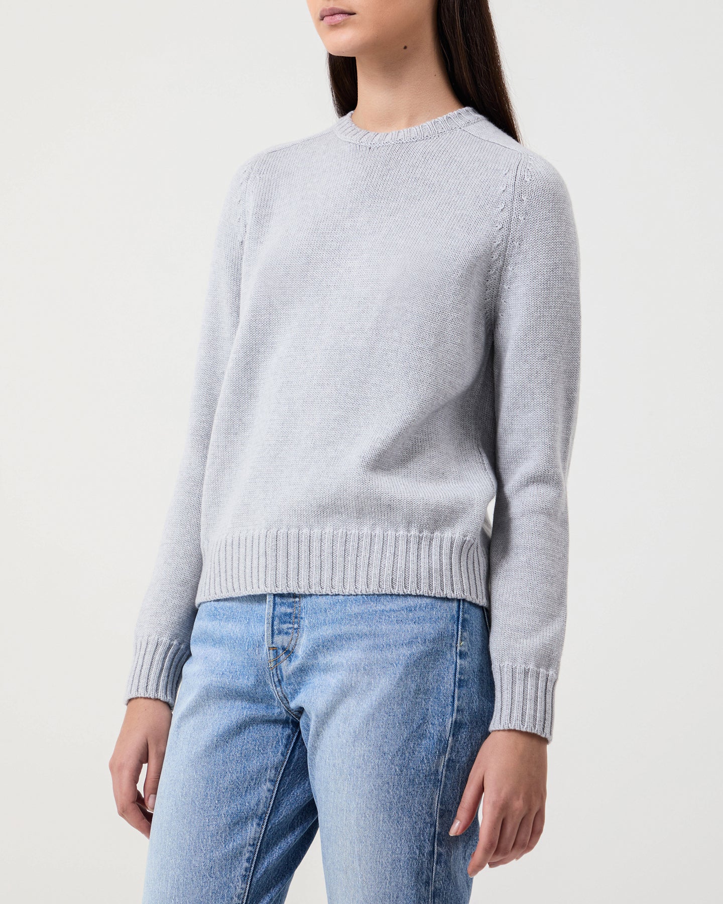 Woman wears Casasola Mia Knitted Merino Wool Saddle Shoulder Crewneck in Grey