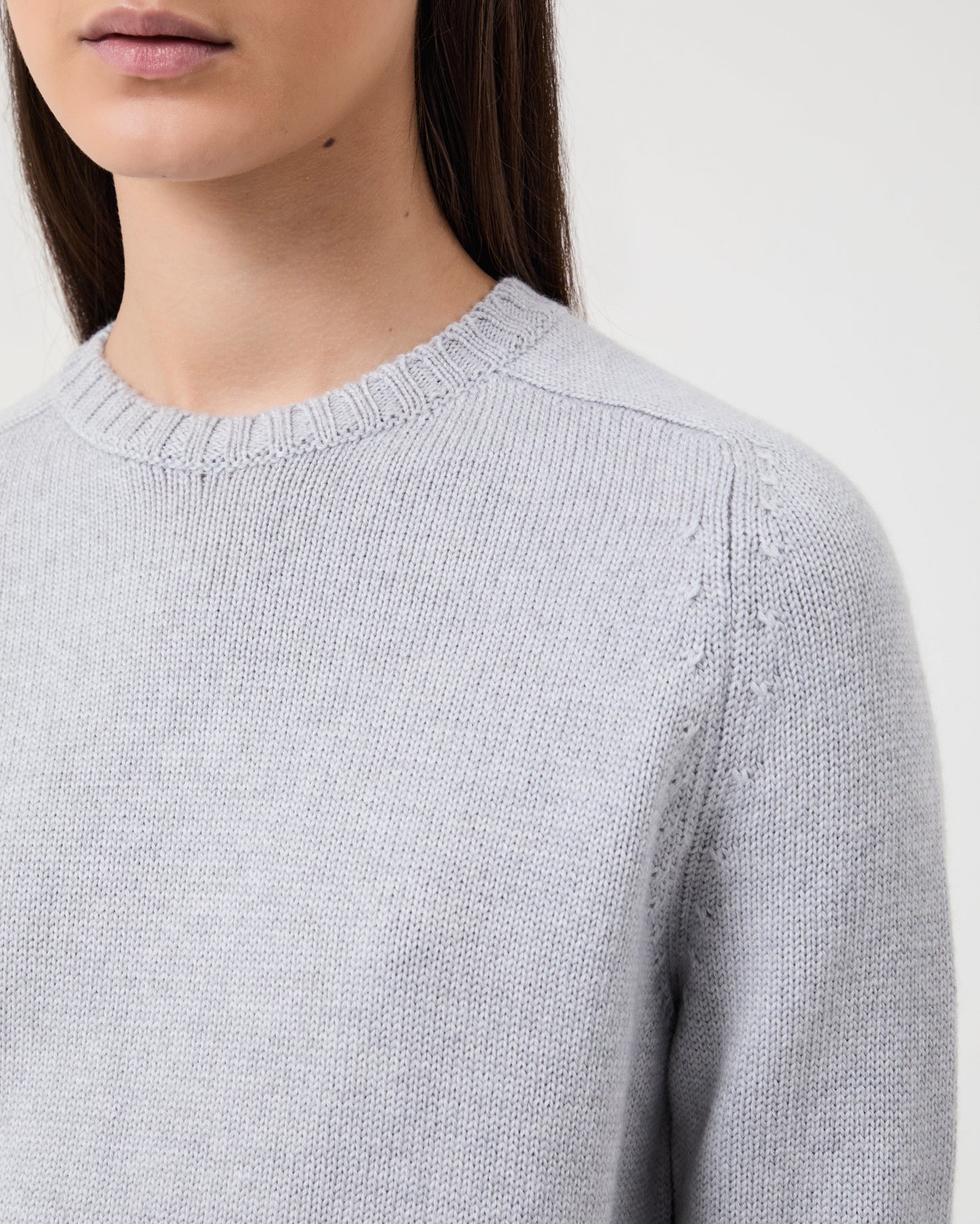 Woman wears Casasola Mia Knitted Merino Wool Saddle Shoulder Crewneck in Grey - detail view