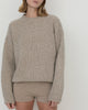Women wearing Casasola Orso beige-colored, oversized, four-ply knitted cashmere-silk boucle sweater with a ribbed mock neckline, with knitted cashmere shorts - front view.